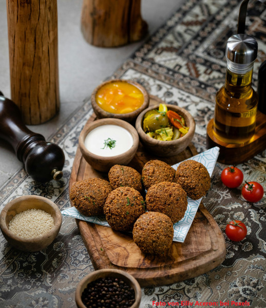 Falafel-auf-einem-Holzbrett-umgeben-von-Sossen-und-Gem-se-in-Sch-sseln